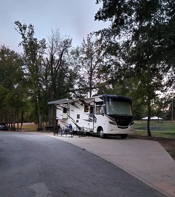 Motorhome parked at a campsite among trees.